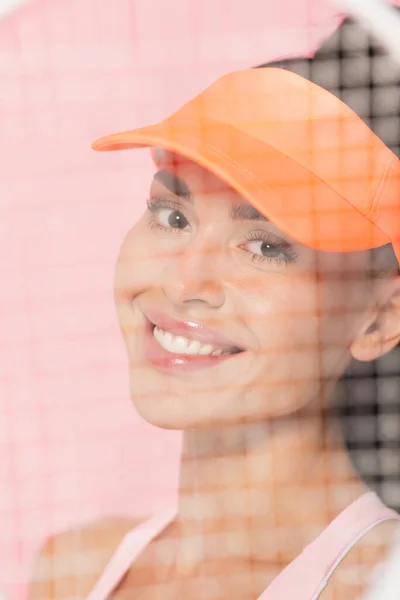 Felice donna in berretto da tennis guardando la fotocamera su rosa — Foto stock