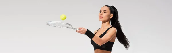 Giovane sportiva con racchetta da tennis e palla mentre gioca isolata sul grigio, striscione — Foto stock