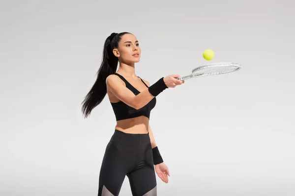 Giovane sportiva con racchetta da tennis e palla mentre gioca isolata sul grigio — Foto stock