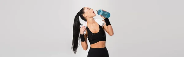 Junge Sportlerin mit Handtuch auf den Schultern, Trinkwasser isoliert auf grau, Banner — Stockfoto
