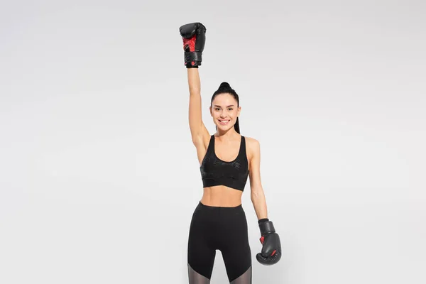 Heureuse sportive en gants de boxe se réjouissant isolée sur gris — Photo de stock