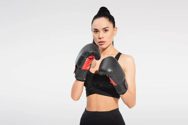 Strong young sportswoman in boxing gloves isolated on grey — Stock Photo