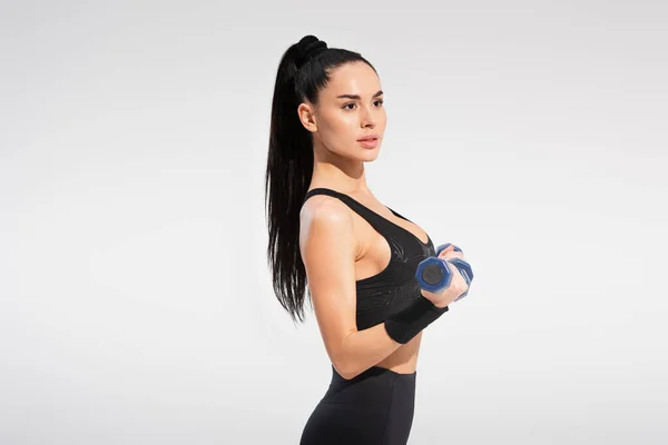 Сильна спортсменка в спортивному одязі вправи з гантелями ізольовані на сірому — стокове фото
