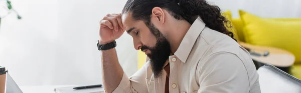 Side view of tired hispanic man sitting with closed eyes and hand near head at home, banner — Stock Photo