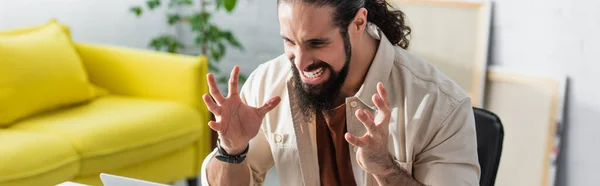 Angry hispanic freelancer gesturing near laptop while working at home, banner — Stock Photo