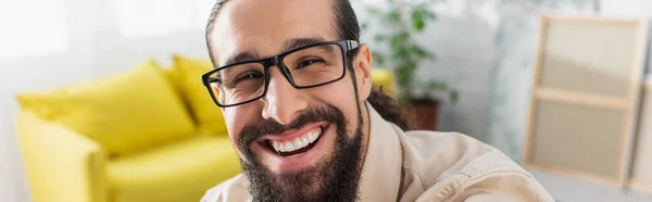 Alegre hombre hispano con anteojos riéndose de la cámara, pancarta - foto de stock