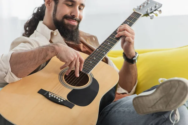 Uomo ispanico sfocato che suona la chitarra acustica a casa — Foto stock