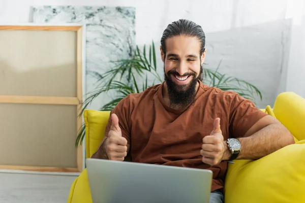 Glücklicher hispanischer Mann zeigt Daumen nach oben während Videochat auf Laptop zu Hause — Stock Photo