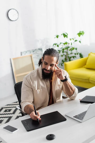 Lateinamerikanische Designerin zeichnet auf Grafik-Tablet, während sie in der Nähe des Laptops zu Hause arbeitet — Stockfoto