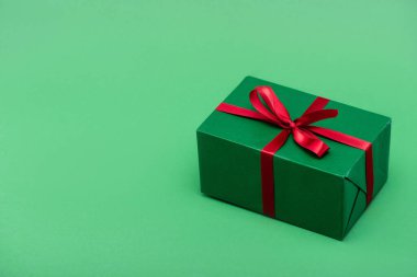 Kırmızı kurdeleli renkli hediye kutusu ve kopyalama alanı olan yeşil arkaplan