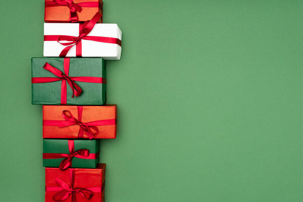 вид сверху на красочные подарочные коробки с красными лентами на зеленом фоне с копировальным пространством
