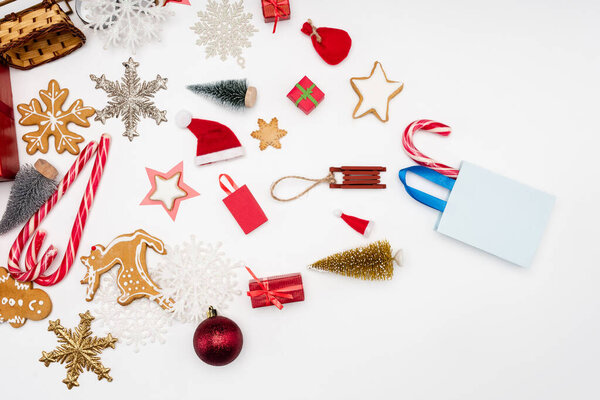 top view of different christmas baubles, candy canes and cookies on white background