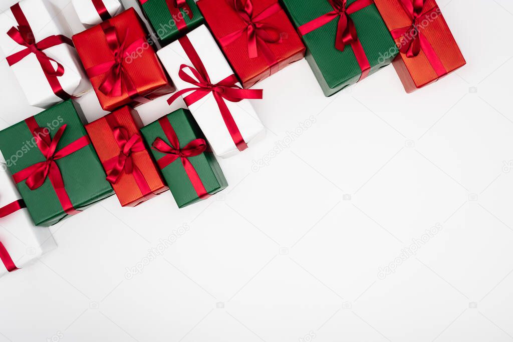 top view of colorful present boxes with red ribbons and bows on white background