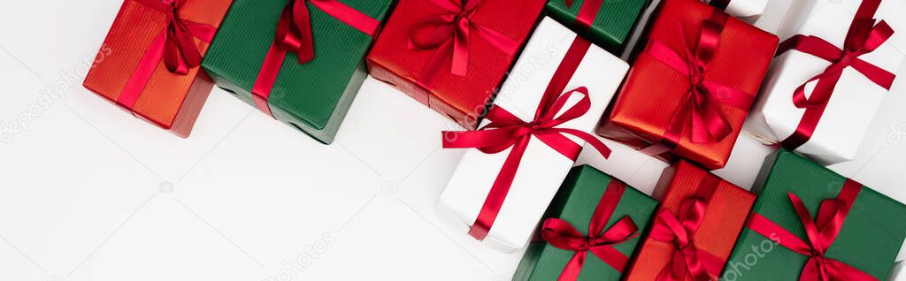 horizontal concept of colorful gift boxes with red ribbons on white background, top view