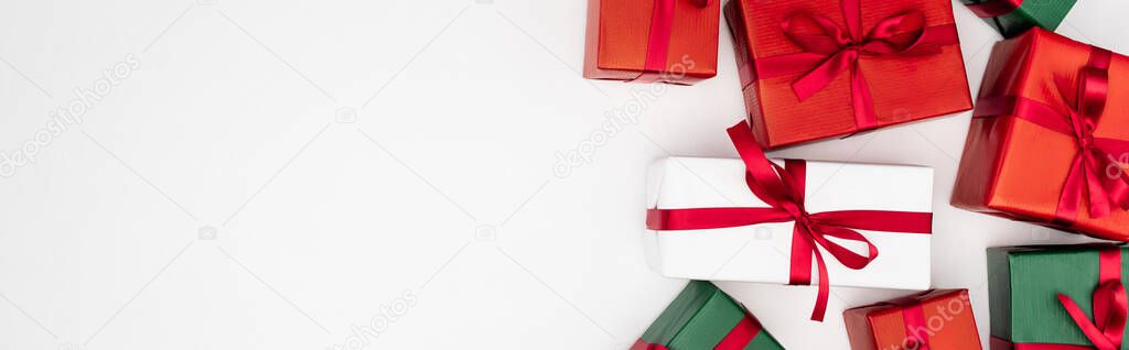 horizontal concept of colorful gift boxes with red ribbons on white background, top view