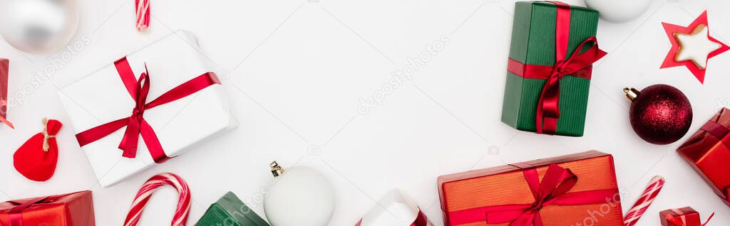 panoramic shot of gift boxes, christmas balls and candy canes on white background