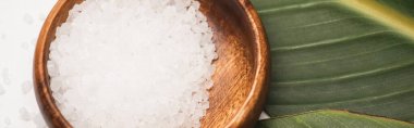 close up view of natural sea salt in wooden bowl on green leaf, banner clipart