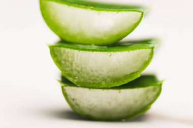 Beyaz yüzeyde kesilmiş aloe vera yapraklarının görüntüsünü kapat