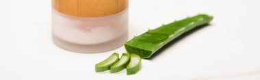 Doğal ev yapımı kozmetik krem kabı kesilmiş aloe vera yaprağı ve beyaz pankartta dilimler