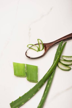 Beyaz üzerinde ev yapımı kozmetik krem ve aloe vera yapraklı ahşap kaşık manzarası.