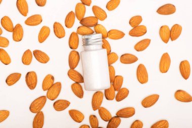 top view of bottle with refreshing lotion near almonds on white surface clipart