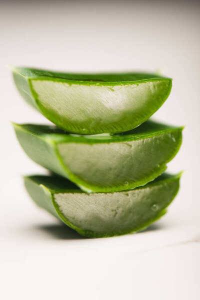 close up view of sliced aloe vera leaves stacked on white surface