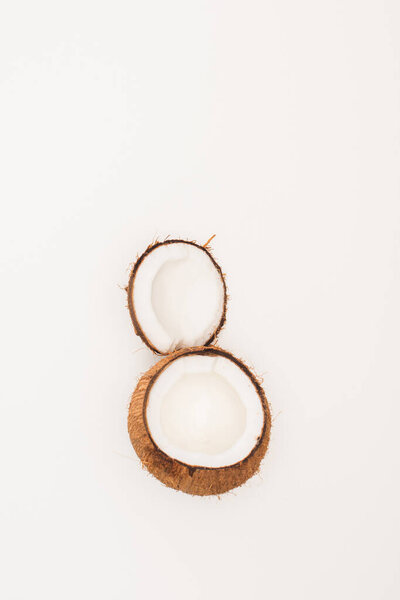 top view of coconut halves on white surface with copy space