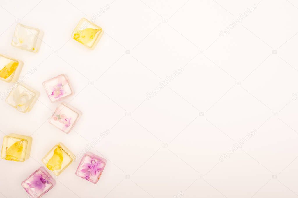 top view of floral and fruit refreshing ice cubes on white background with copy space