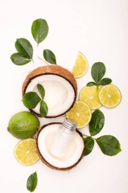 Limon manzarası, hindistan cevizi yarımları, bir şişe losyon ve beyaz gül yaprakları.