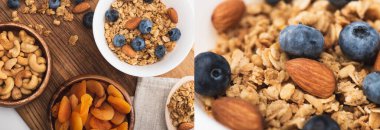 Lezzetli granola kolajı fındıklı, kurutulmuş kayısı ve beyaz arka planda ahşap tahtada yabanmersini, afiş.