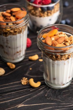Kurutulmuş kayısı, fındık ve yoğurtlu lezzetli granola. Arka planda bulanık cam bardak.