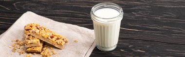 Tahta yüzeydeki süt bardağının yanında nefis müsli barlar, pankart.