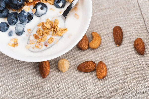 closeup of delicious granola with nuts, yogurt, blueberry in bowl with spoon