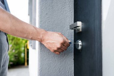 Cropped view of man with key opening door on blurred background clipart