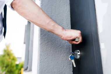 Cropped view of broker opening door on blurred background clipart