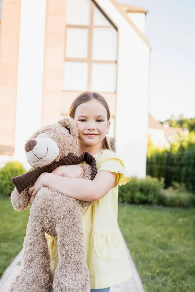 Smiling Girl Looking Camera While Hugging Teddy Bear Blurred Home — Stock Photo, Image