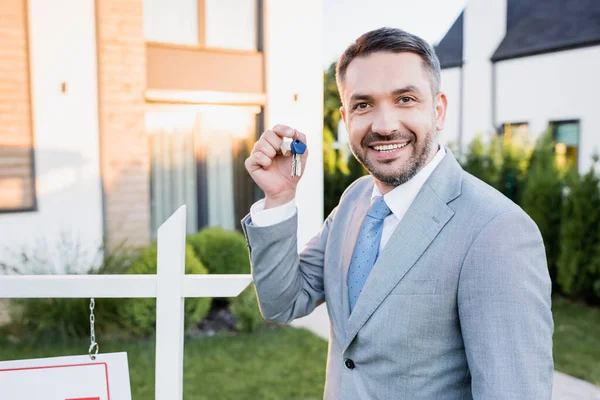 Bróker Feliz Mostrando Las Teclas Mientras Mira Cámara Fondo Borroso — Foto de Stock