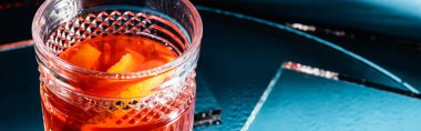 Viski ve portakallı karışık alkol kokteyli mavi ve pankartta