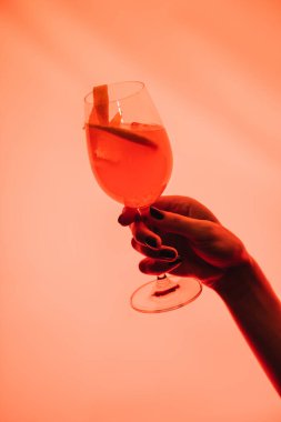 Kadın elinde bardakla karışık kokteyl ve pembe üzerine portakal. 