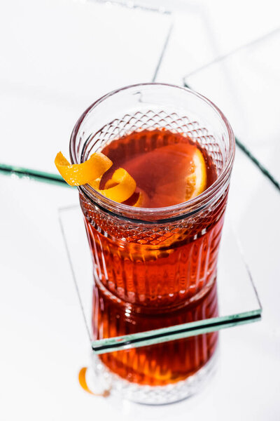 high angle view of orange peel in glass with alcohol cocktail on white surface