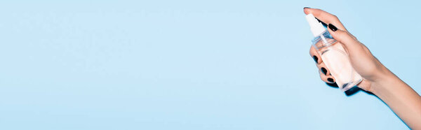 обрезанный вид женщины с помощью дезинфицирующего спрея для рук на синий, баннер