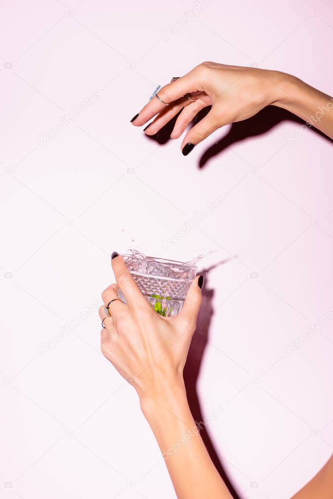 cropped view of woman throwing lime in glass with alcohol drink on white