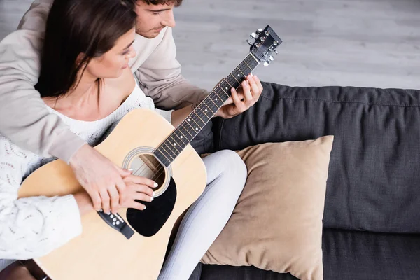 Visão Alto Ângulo Jovem Ensinando Namorada Tocar Guitarra Acústica Casa — Fotografia de Stock