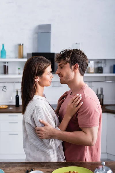 Side View Young Couple Hugging Kitchen Table Blurred Foreground — Stock Photo, Image