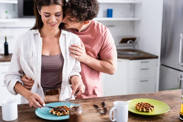 Jovem Abraçando Namorada Sorridente Perto Waffles Copos Mesa Cozinha — Fotografia de Stock