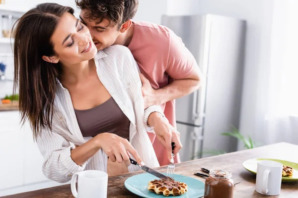 Man Kissing Smiling Girlfriend Cutting Waffle Chocolate Spread Cups Table — Stock Photo, Image