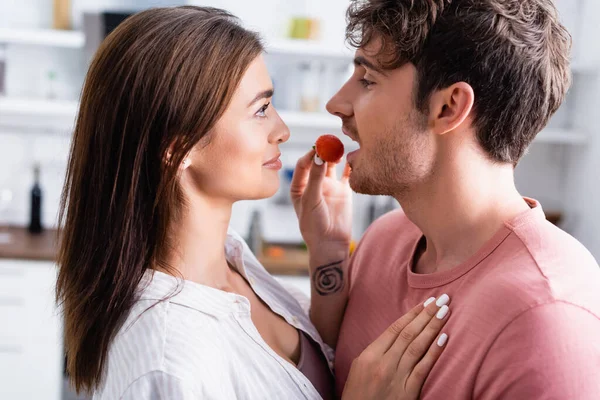 Morena Mujer Sosteniendo Fresa Cerca Novio Con Boca Abierta Cocina — Foto de Stock