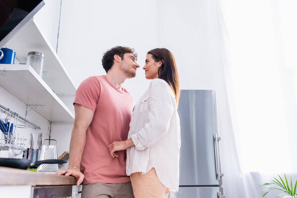 Young couple looking at each other near kitchenware on blurred foreground 