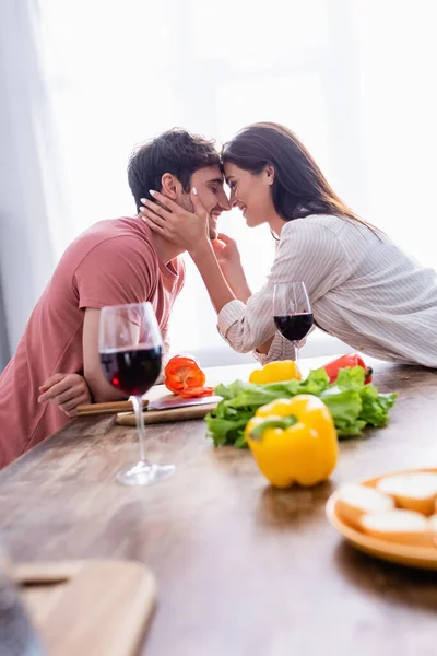 Smiling Woman Touching Face Boyfriend Wine Vegetables Blurred Foreground — Stock Photo, Image