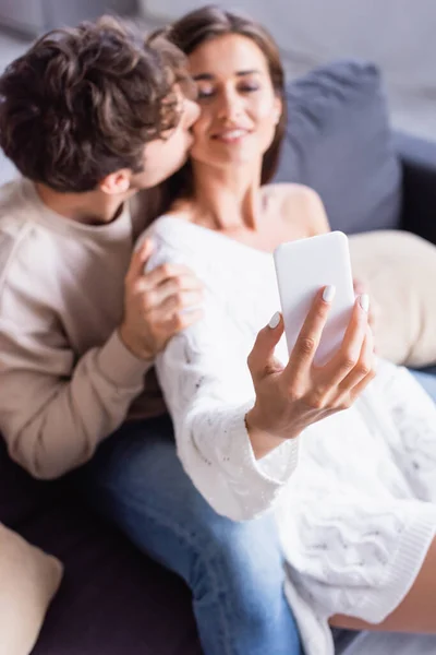 Smartphone Hand Cheerful Woman Taking Selfie Boyfriend Kissing Blurred Background — Stock Photo, Image